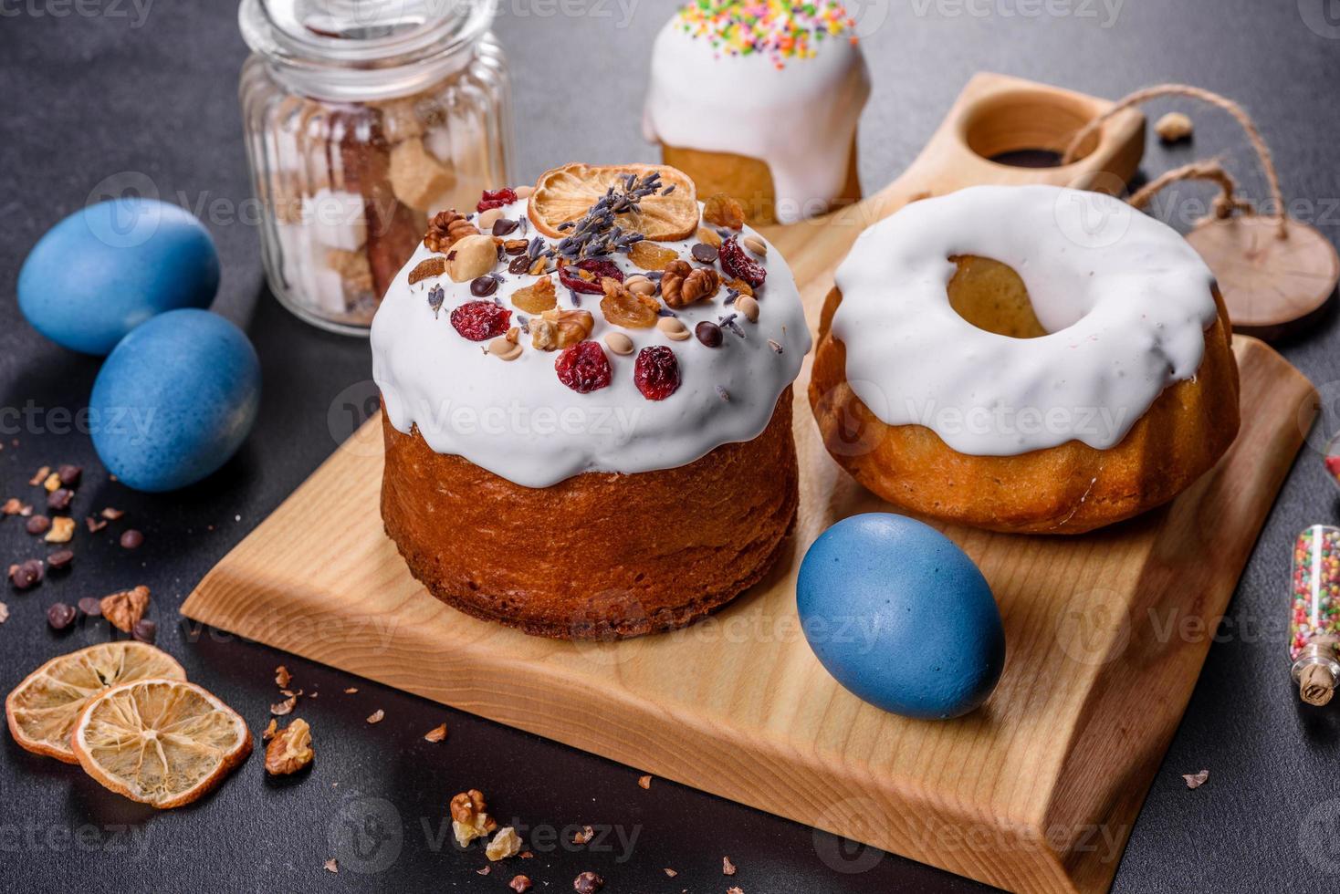 torte festive con glassa bianca, noci e uvetta con uova di Pasqua sulla tavola festiva foto