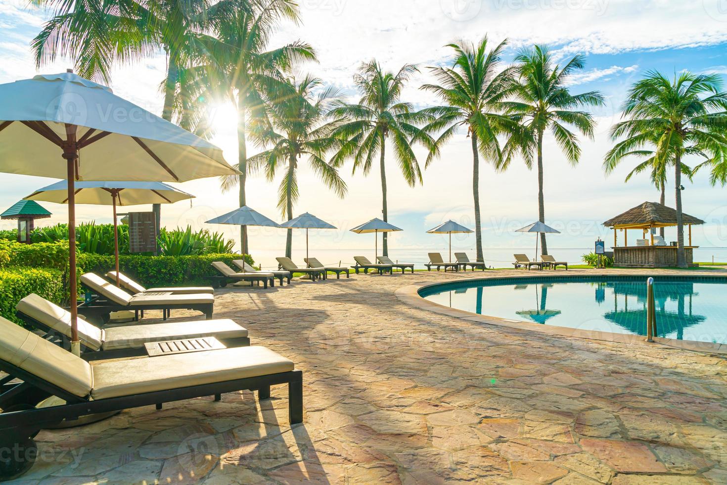 ombrellone e sedia intorno alla piscina in hotel resort per viaggi di piacere e vacanze vicino alla spiaggia dell'oceano del mare foto