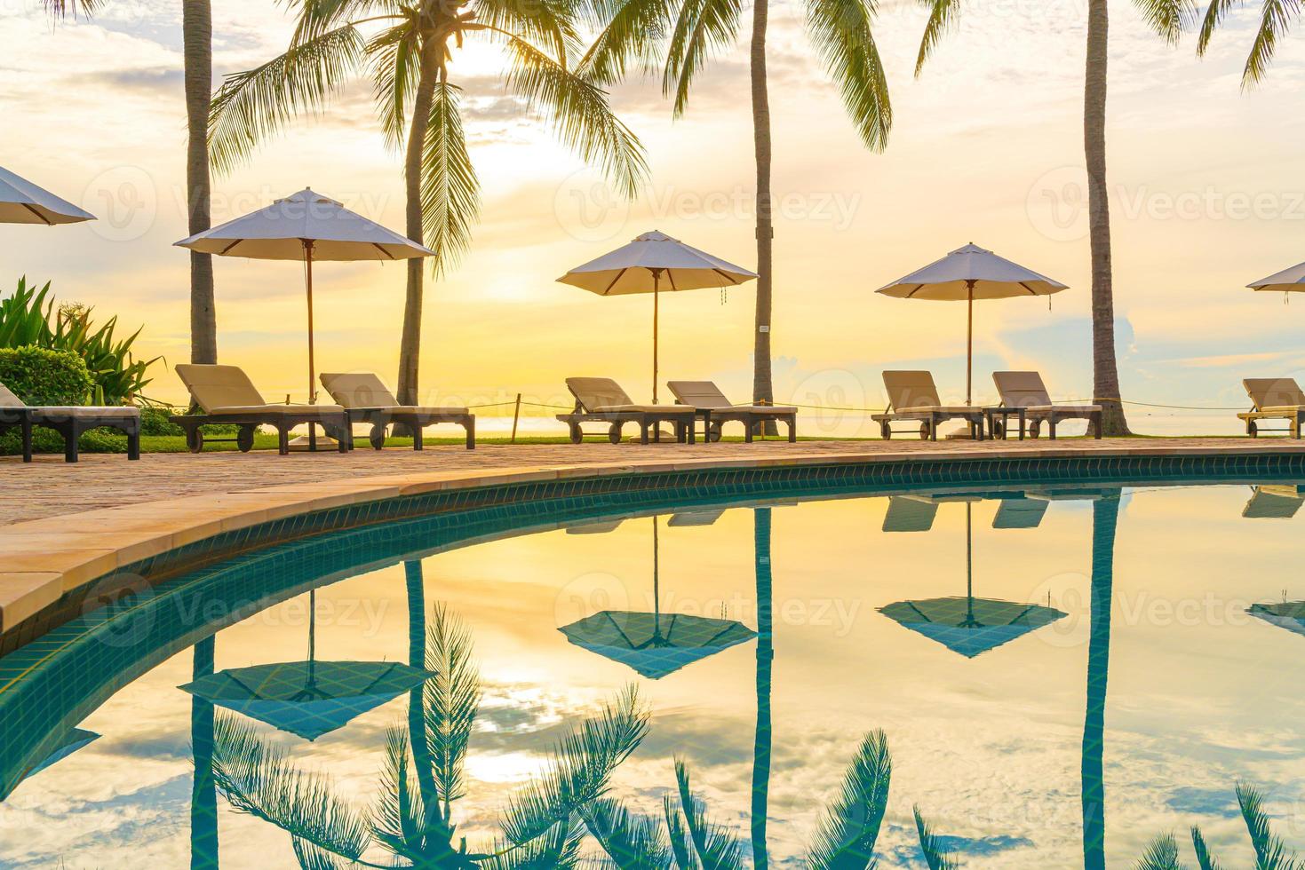 ombrellone e sedia intorno alla piscina in hotel resort per viaggi di piacere e vacanze vicino alla spiaggia dell'oceano del mare foto