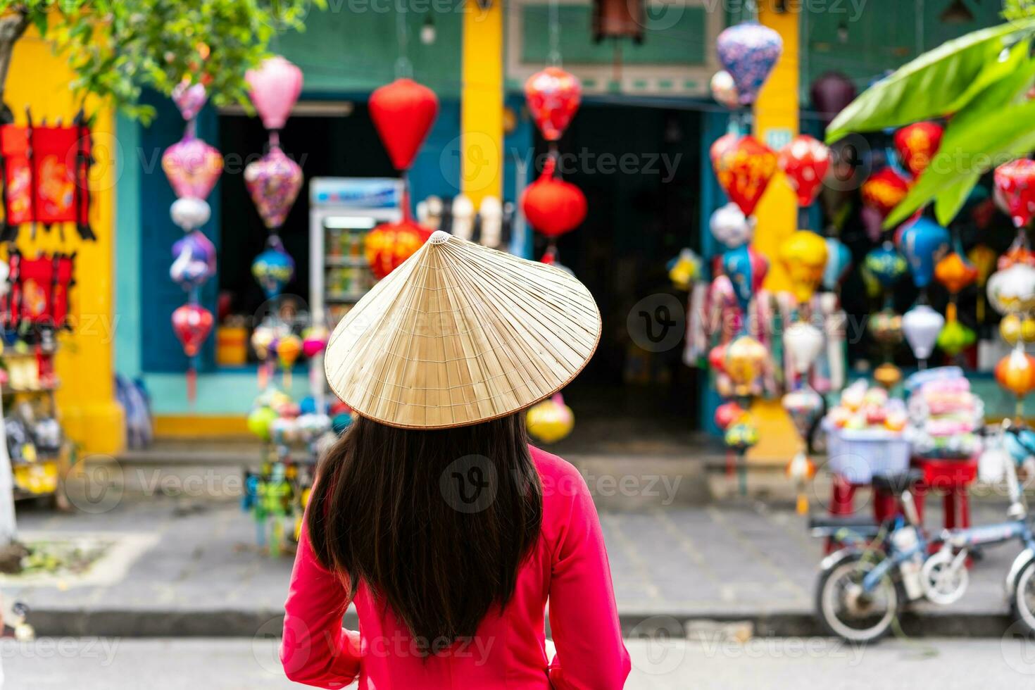 giovane femmina turista nel vietnamita tradizionale vestito guardare a un' souvenir negozio nel Hoi un antico cittadina foto