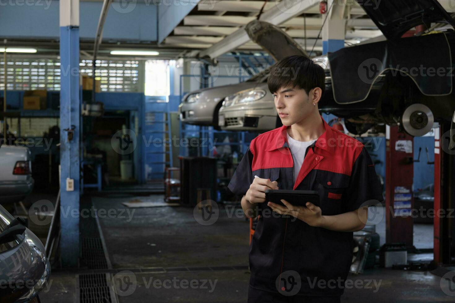 uno maschio asiatico professionale meccanico, supervisore ingegnere, ispeziona riparazione opera liste di controllo con tavoletta a box auto, servizio auto Manutenzione, e fissaggio specialista occupazioni nel auto trasporto industria. foto