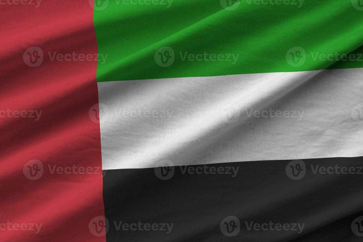 unito arabo Emirates bandiera con grande pieghe agitando vicino su sotto il studio leggero al chiuso. il ufficiale simboli e colori nel bandiera foto