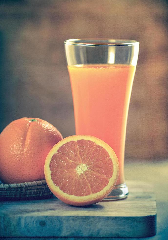 bicchiere di succo d'arancia e arance fresche su legno. foto in stile retrò