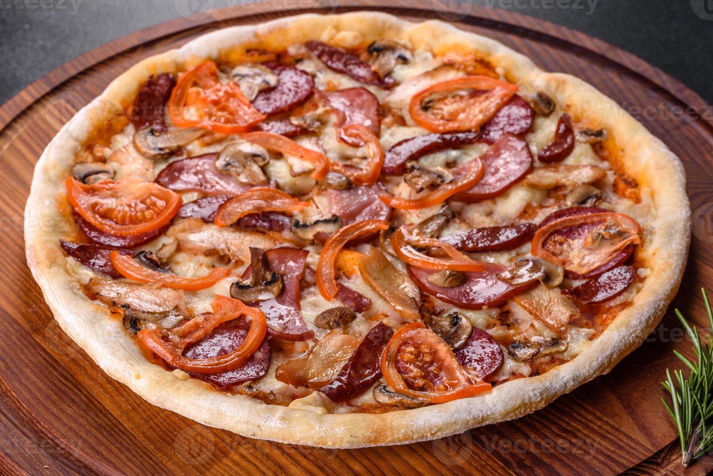 pizza fresca e deliziosa fatta in un forno a focolare con salsiccia, pepe e pomodori foto