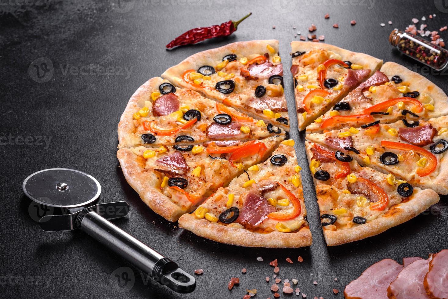 pizza fresca e deliziosa fatta in un forno a focolare con olive, peperoncino e prosciutto foto