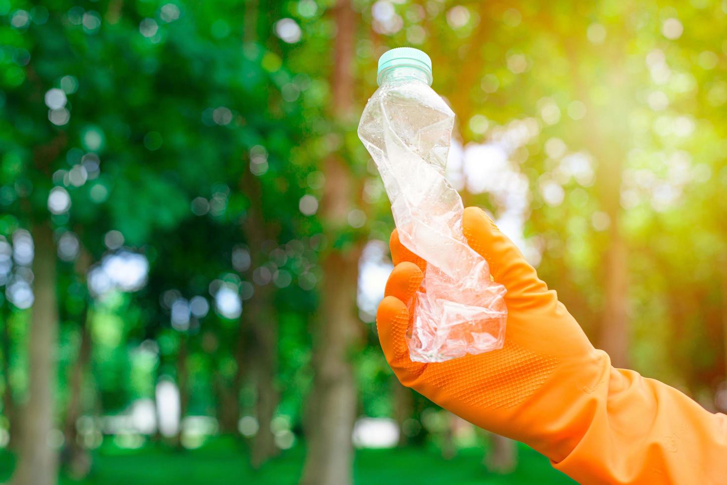 mano dell'uomo volontario che raccoglie una bottiglia di plastica foto