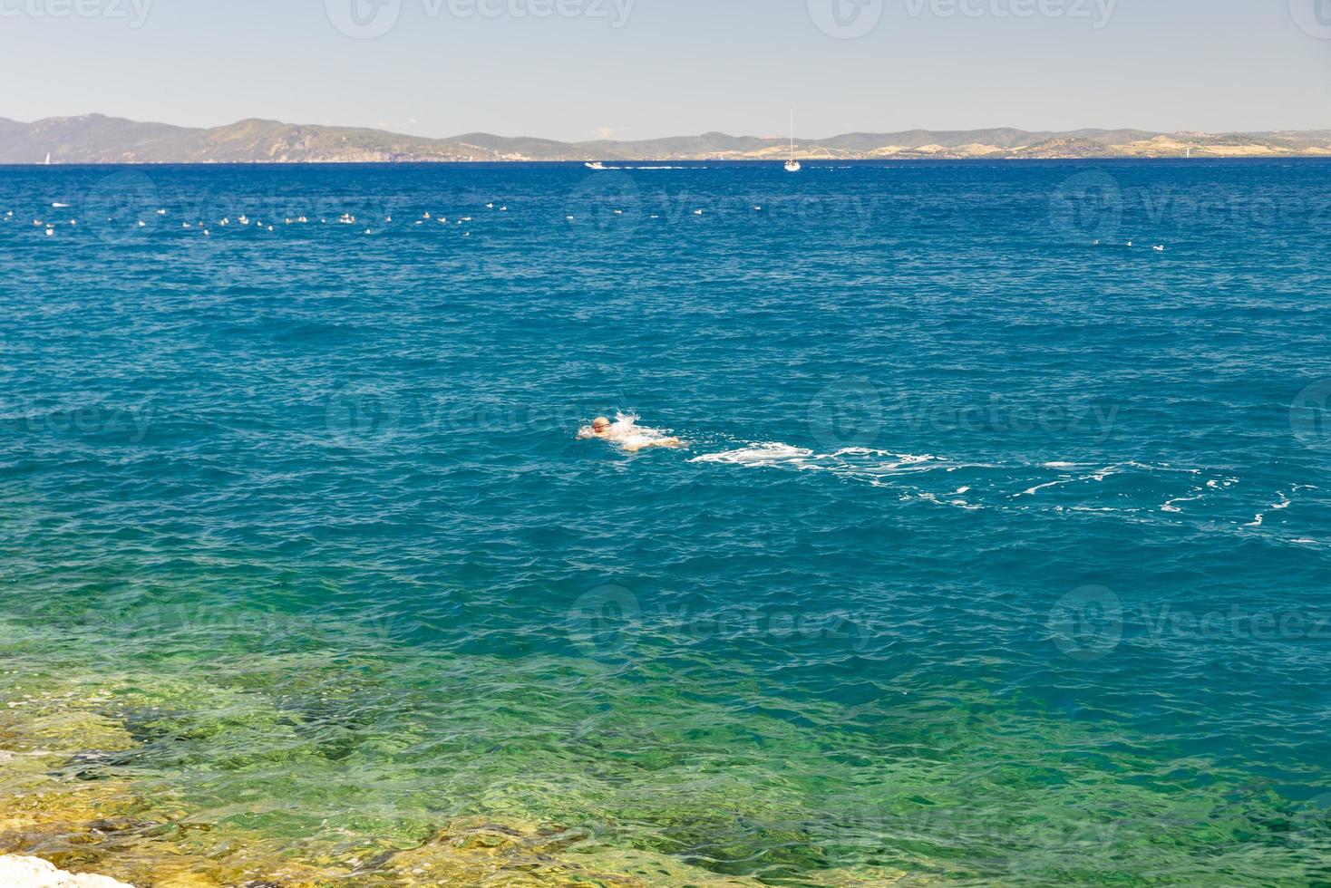 Uomo che nuota in mare a porto santo stefano, italia foto