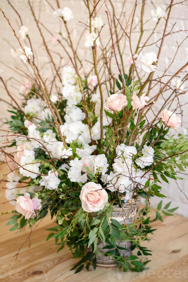 decorazioni di rami con bellissimi fiori rosa e bianchi nel cesto sullo sfondo di un muro di mattoni bianchi foto