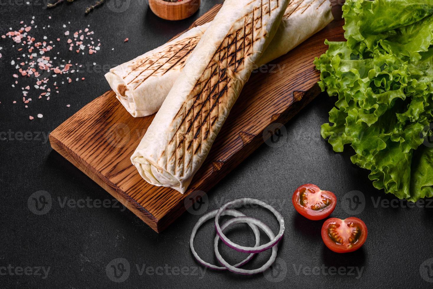 delizioso shawarma fresco con carne e verdure su un tavolo di cemento scuro foto