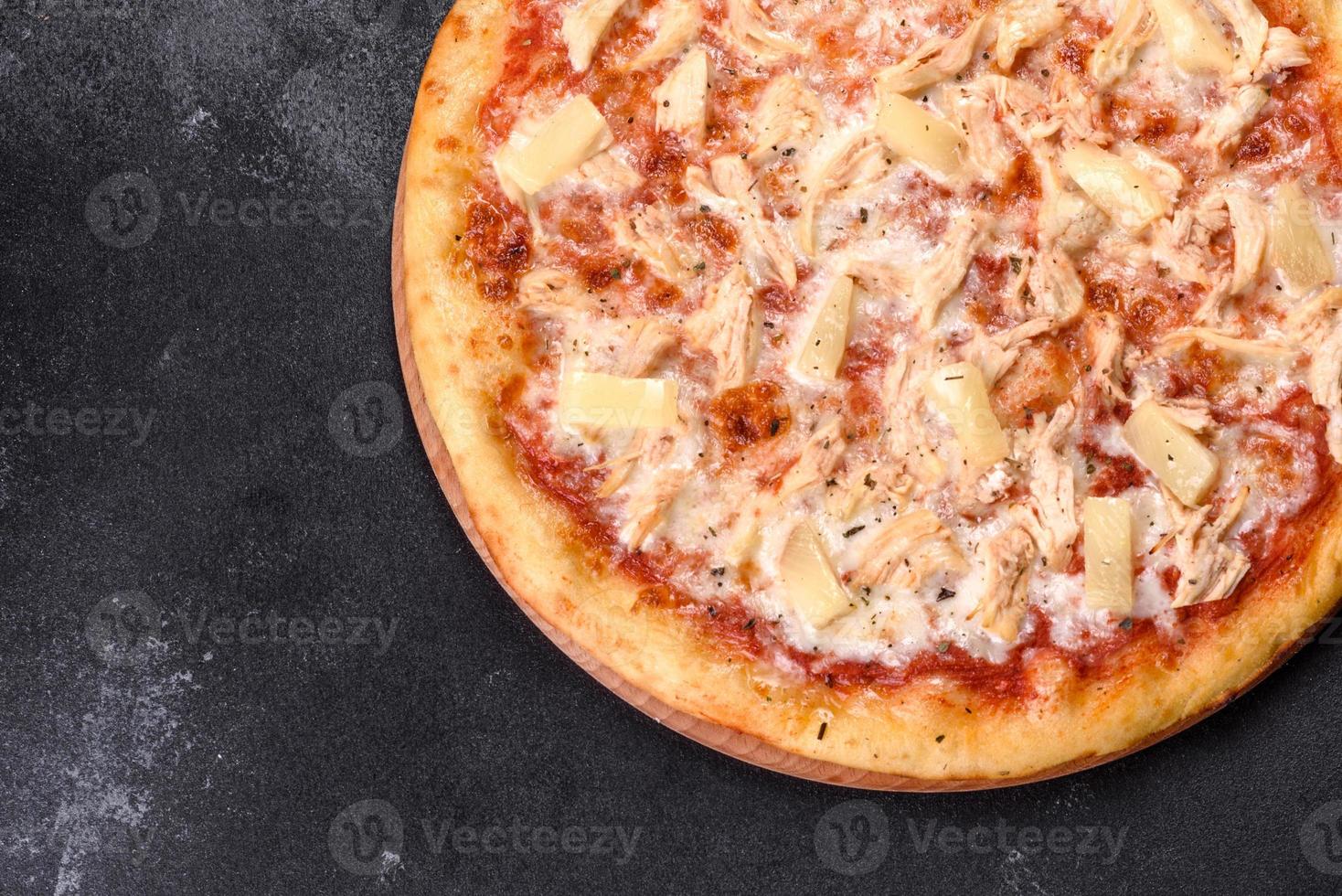 gustosa pizza fresca al forno con pomodori, formaggio e ananas su uno sfondo di cemento scuro foto