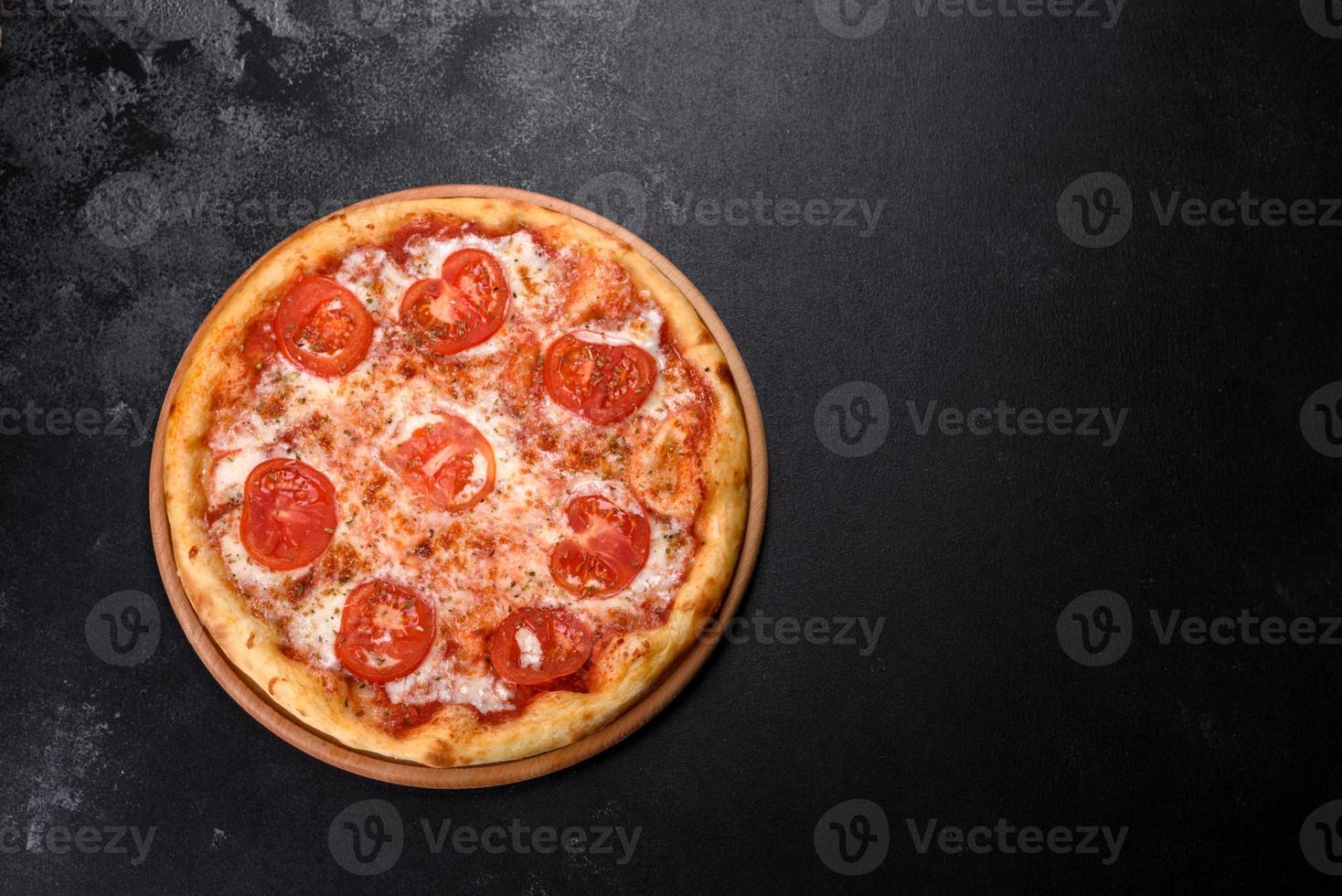 gustosa pizza fresca al forno con pomodori, formaggio e basilico su fondo di cemento foto
