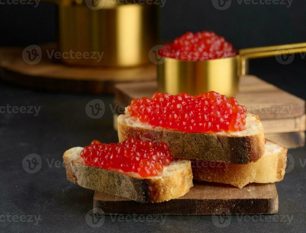 rosso caviale su fette di bianca Grano pane su un' nero tavolo, concetto di lusso e buongustaio cucina foto