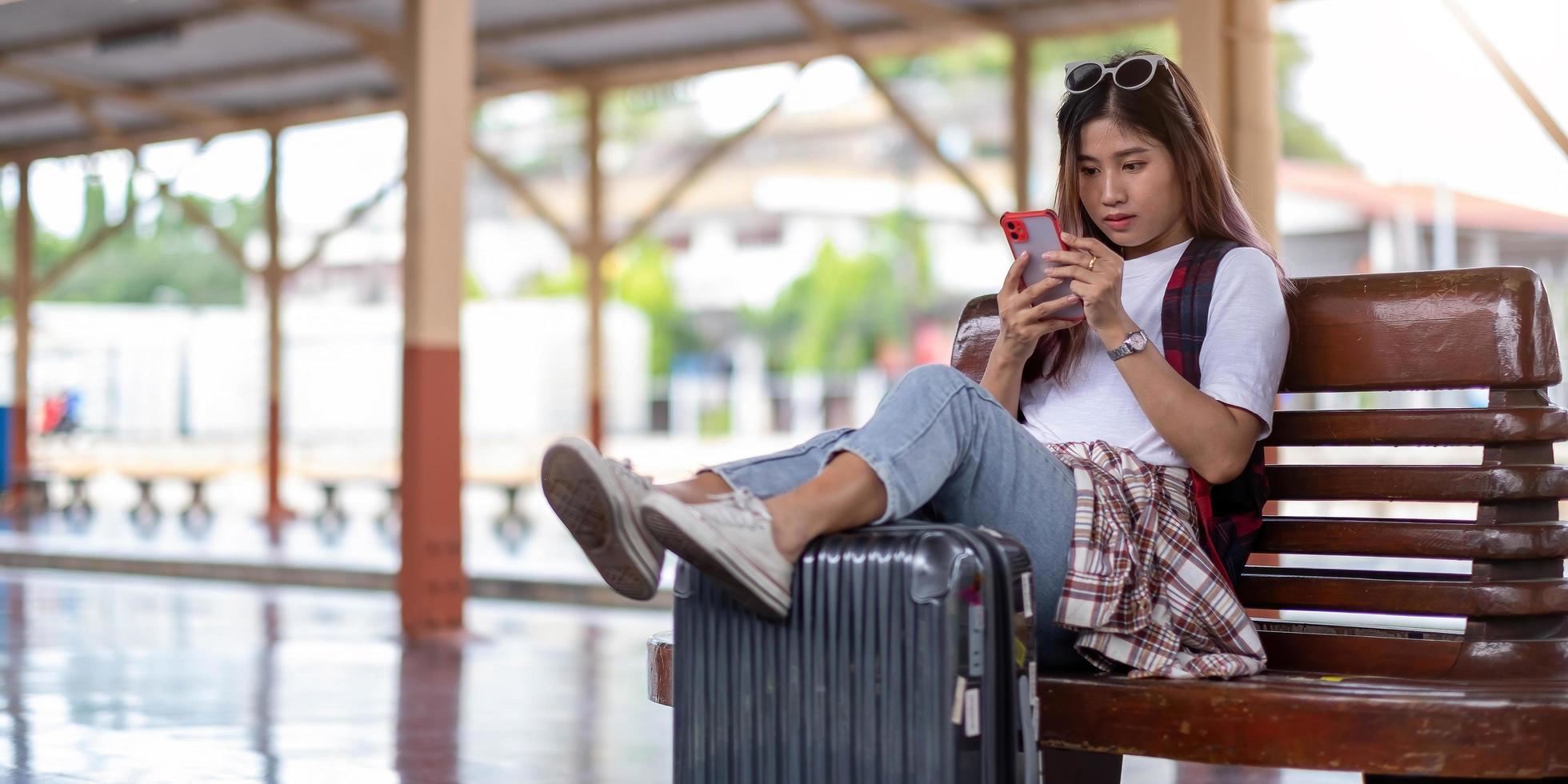 giovane donna che usa il suo smartphone mentre aspetta il treno foto