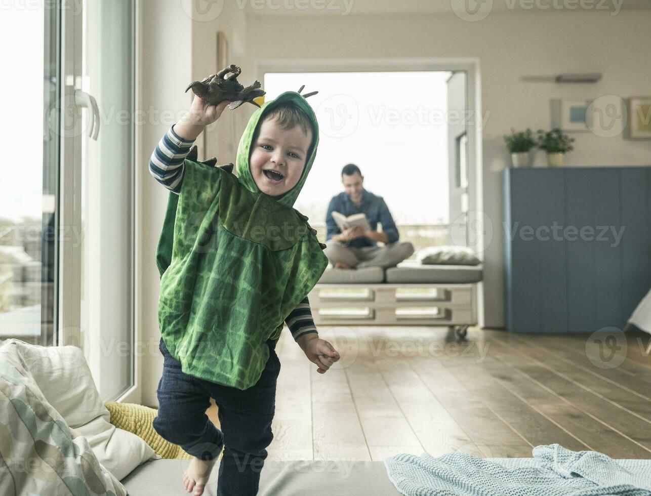 contento ragazzo nel un' costume giocando con giocattolo figura a casa foto