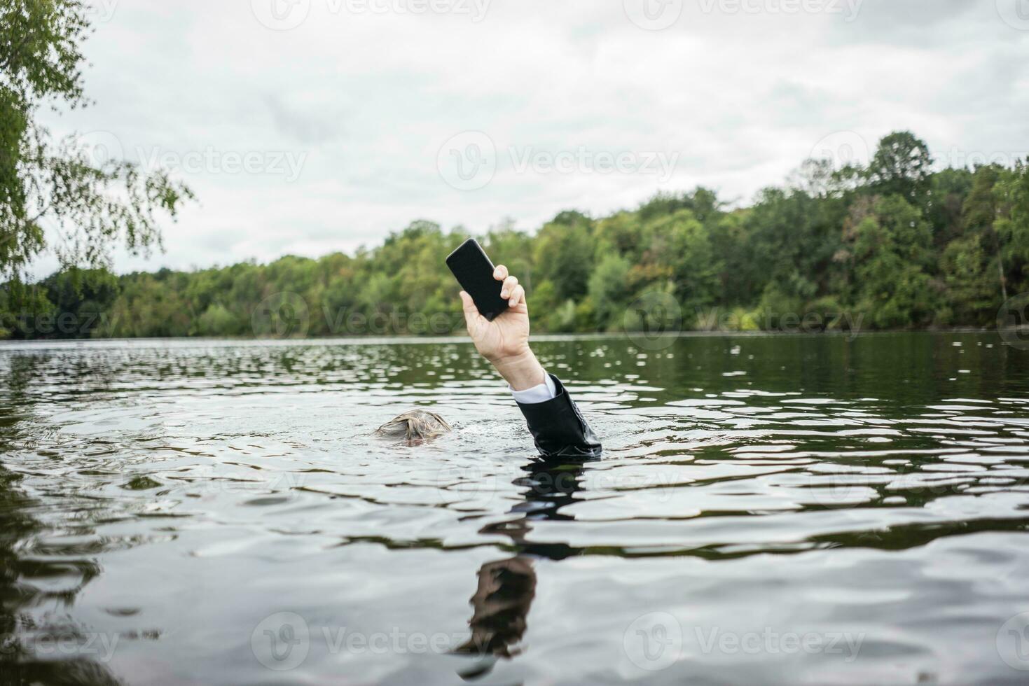 di uomo d'affari mano Tenere cellula Telefono dentro un' lago foto