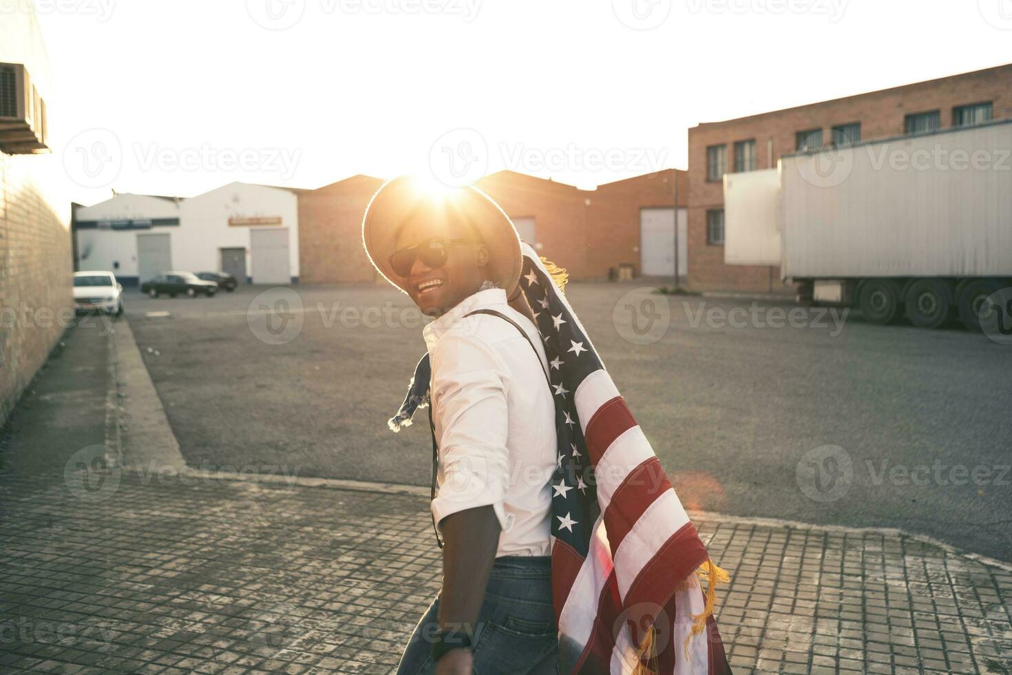 ridendo giovane uomo con americano bandiera a controluce foto
