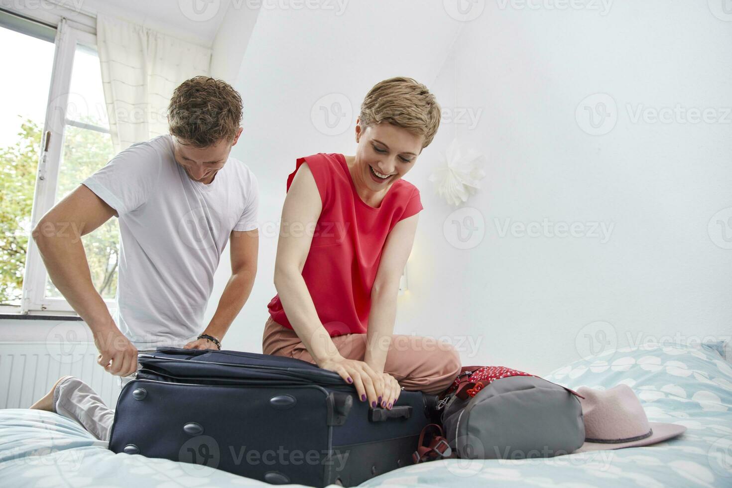 contento coppia Imballaggio valigia per estate vacanza su letto foto