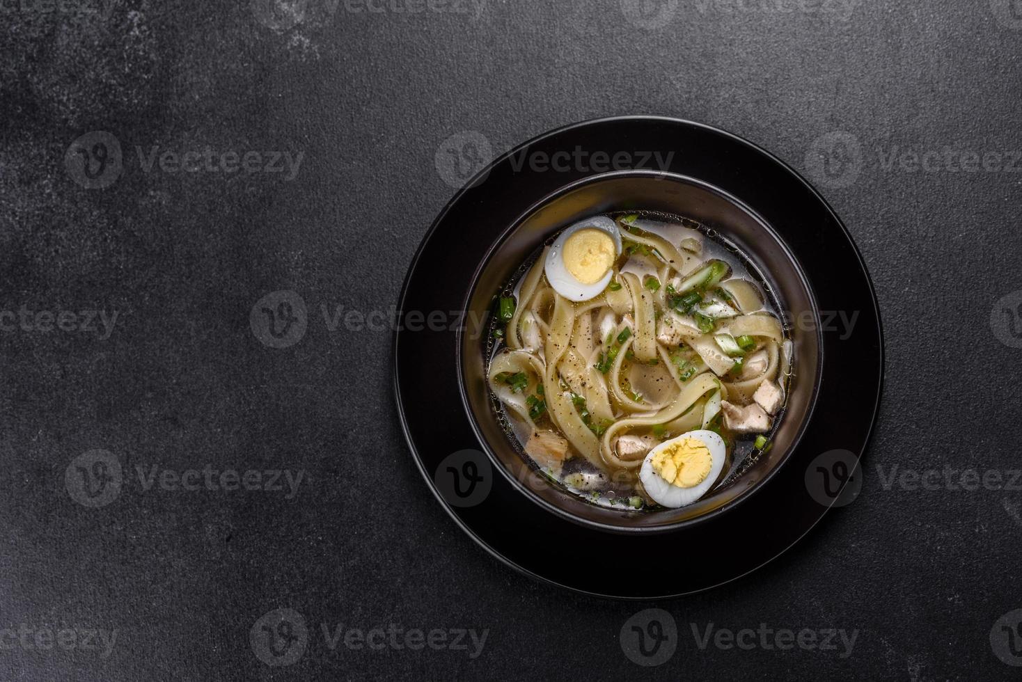 zuppa calda deliziosa fresca con pasta e uova di quaglia in un piatto nero foto