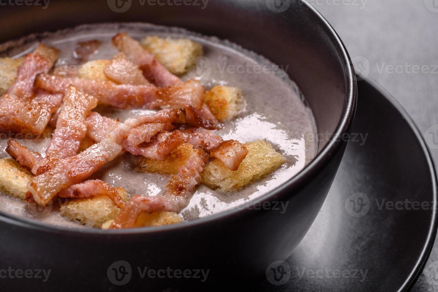 zuppa di purea calda deliziosa fresca con funghi e pancetta in un piatto nero foto