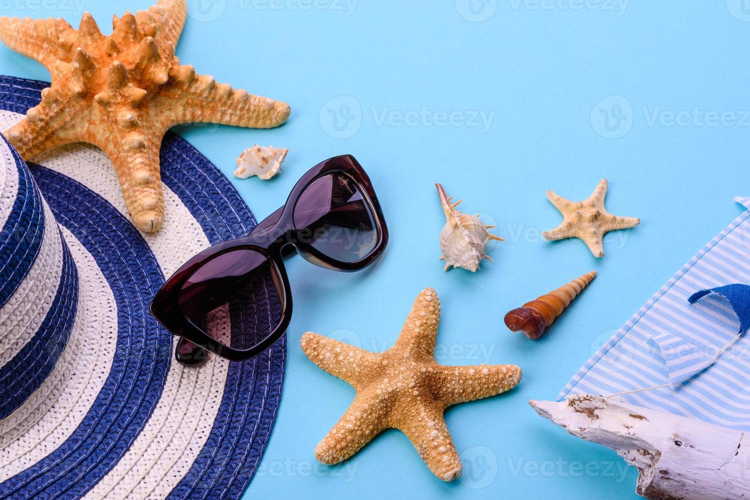 occhiali e cappello con conchiglie e stelle marine su sfondo colorato foto