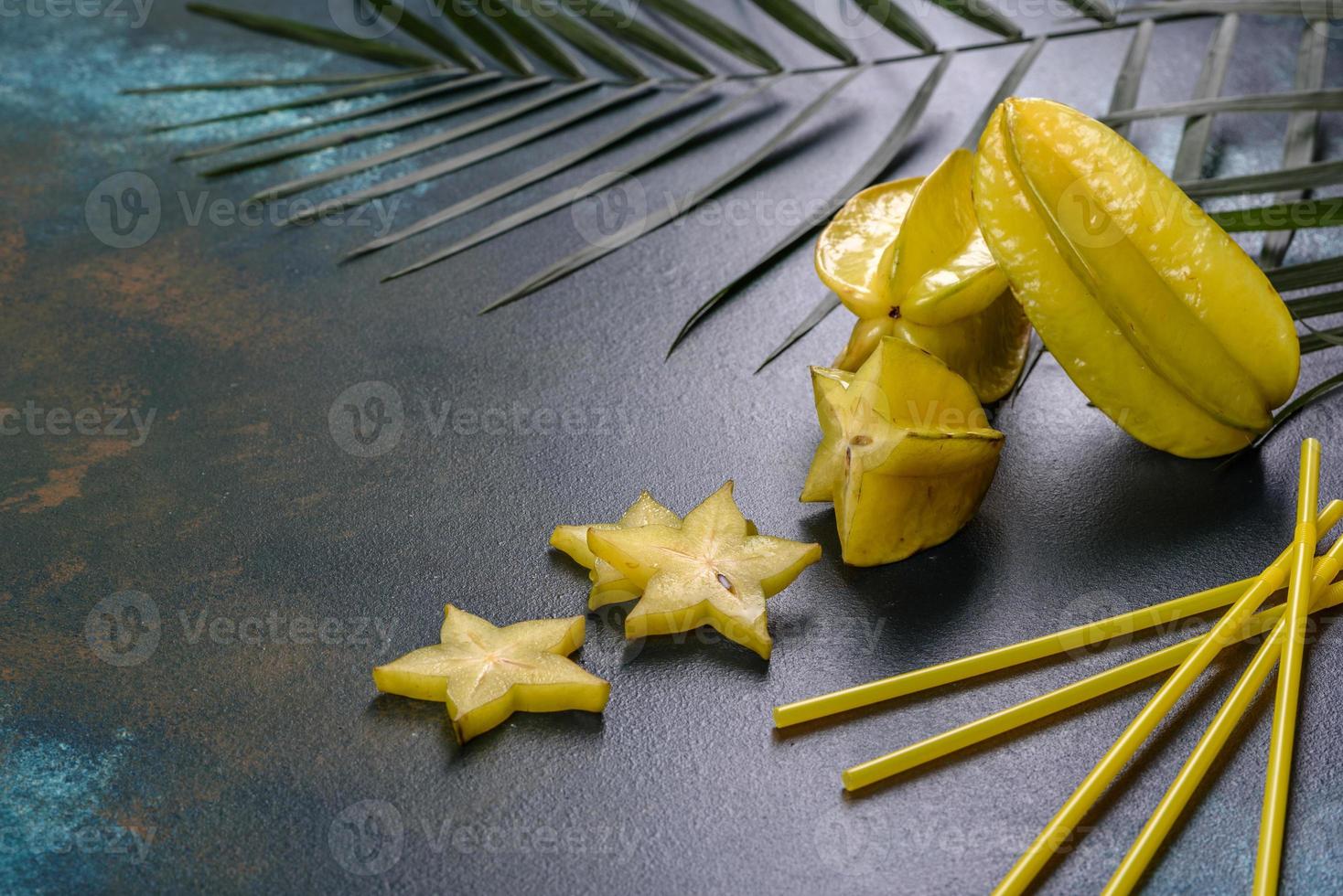 carambola di frutta, accessori da spiaggia e fogliame di una pianta tropicale su carta colorata foto