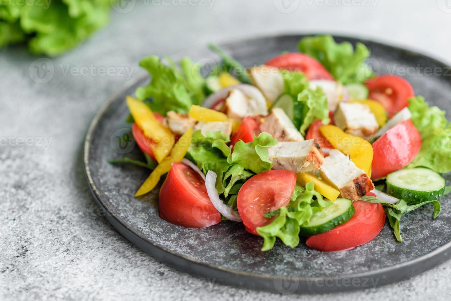 deliziosa insalata fresca con pollo, pomodoro, cetriolo, cipolle e verdure con olio d'oliva foto