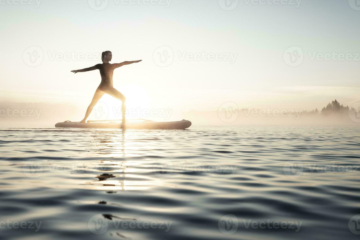 donna praticante pagaia tavola yoga su lago Kirchsee nel il mattina, cattivo toelz, Baviera, Germania foto