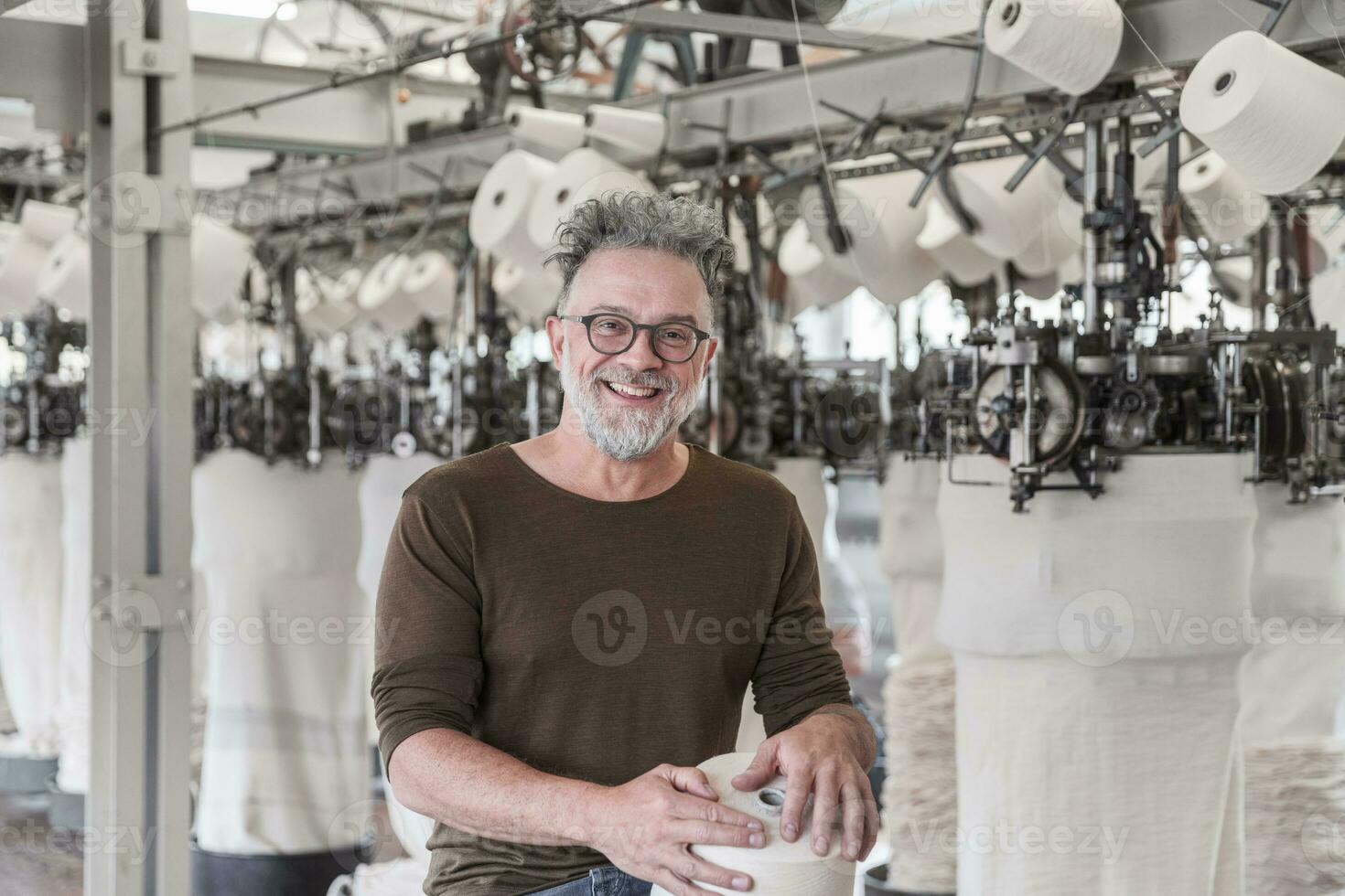 ritratto di un' contento maturo uomo nel un' tessile fabbrica foto