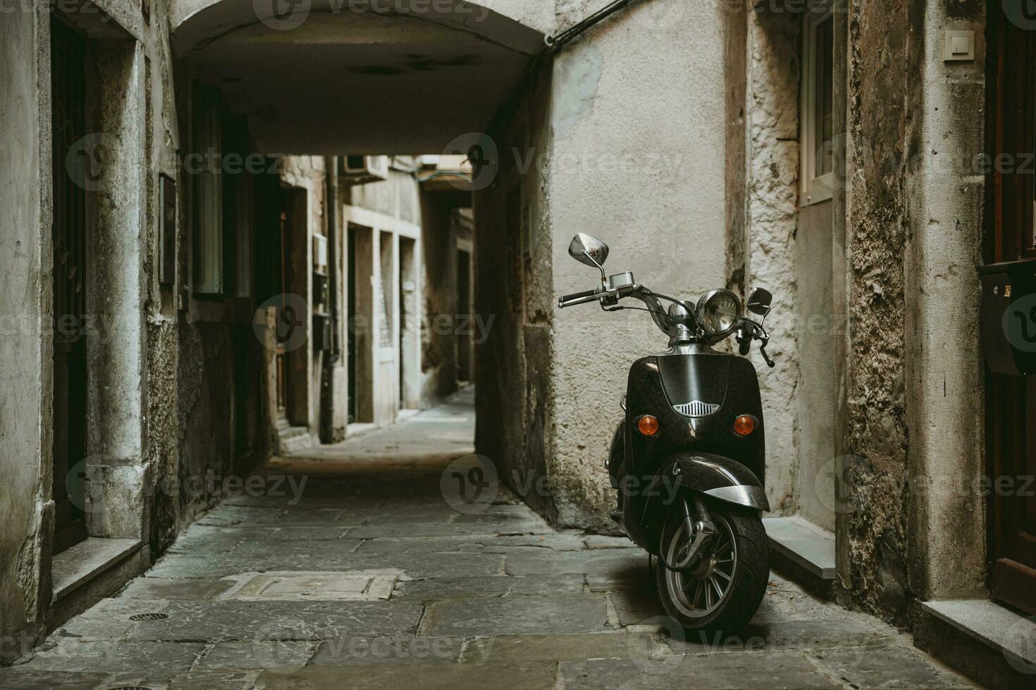 solitario parcheggiata retrò scooter nel davanti di uno Casa nel vecchio vuoto stretto vicolo con pietra strada di storico cittadina di pirano nel slovenia foto