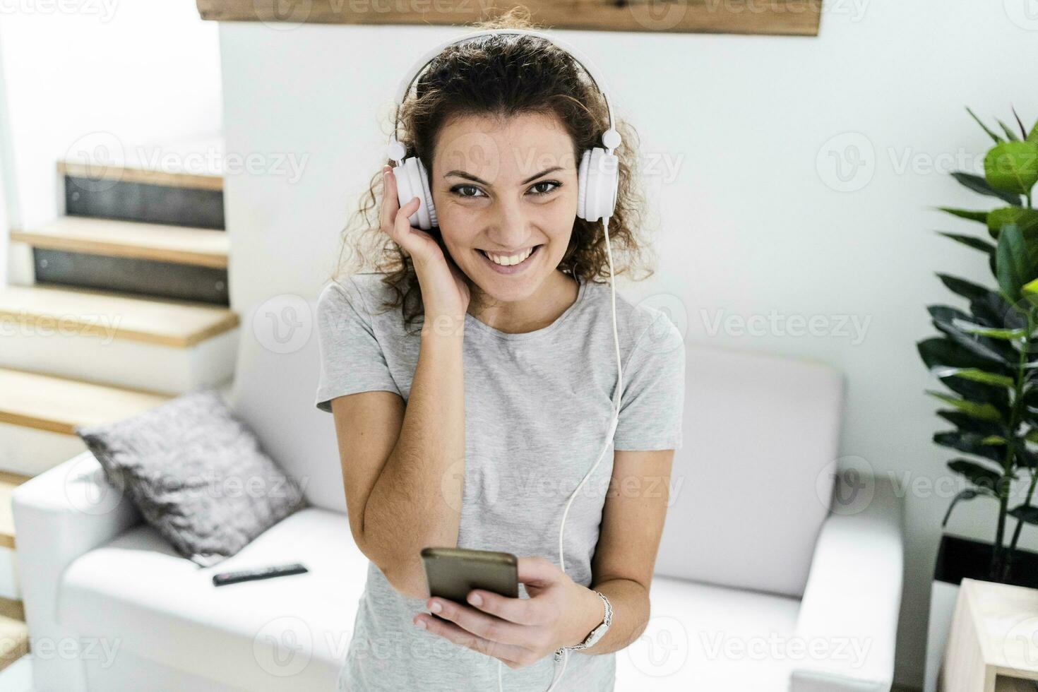 ritratto di sorridente giovane donna ascoltando musica con cuffie e cellula Telefono foto