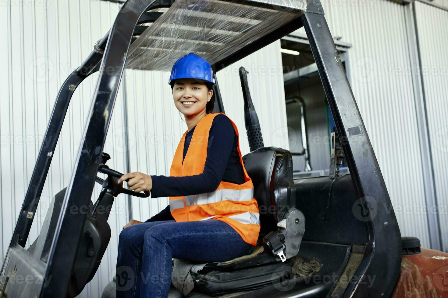 ritratto di fiducioso femmina lavoratore su carrello elevatore a forca nel fabbrica foto