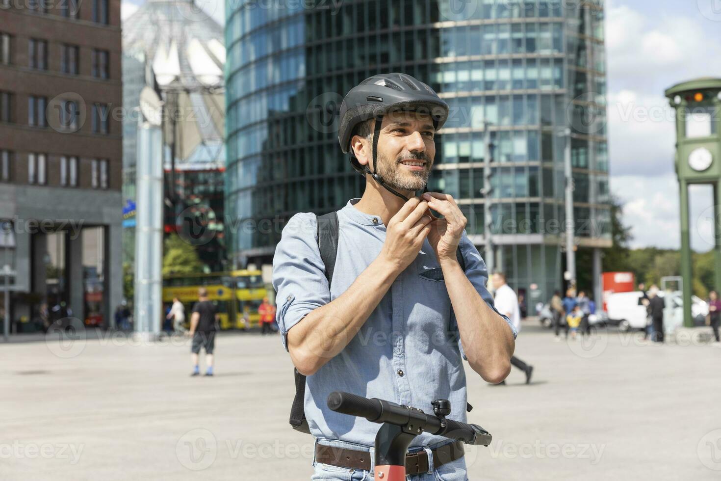 uomo fissaggio il casco prima equitazione su elettrico scooter, Berlino, Germania foto