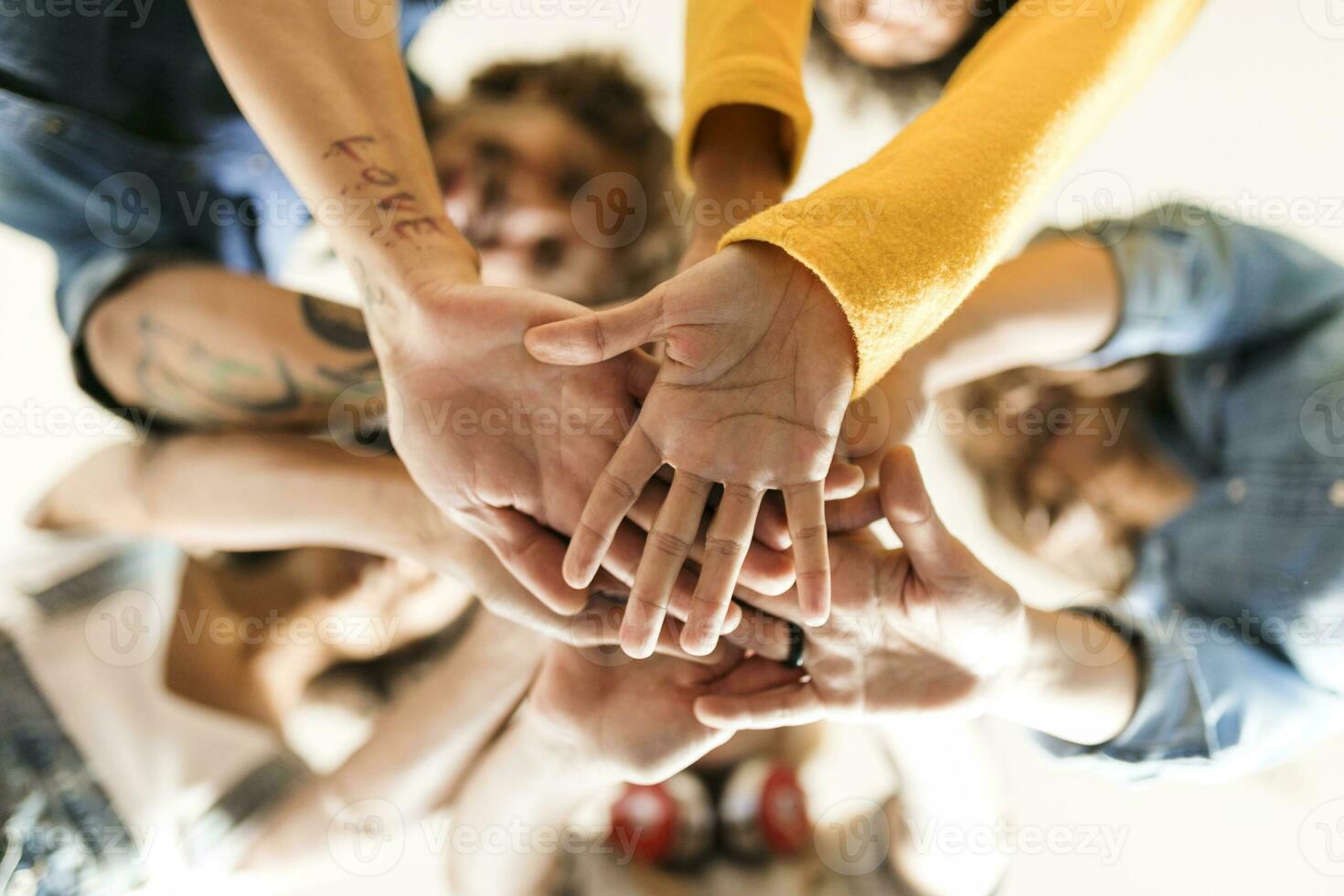 gruppo di contento amici huddling e impilamento mani foto