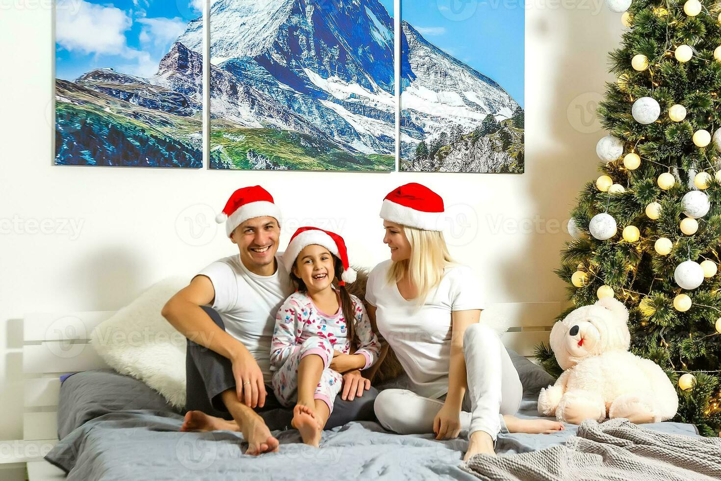 famiglia seduta su letto nel Camera da letto a Natale foto