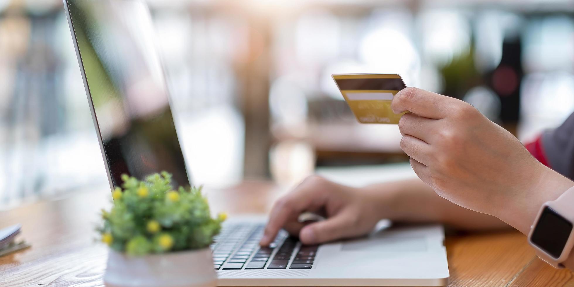 donna che usa il computer e tiene in mano una carta di credito per lo shopping online foto