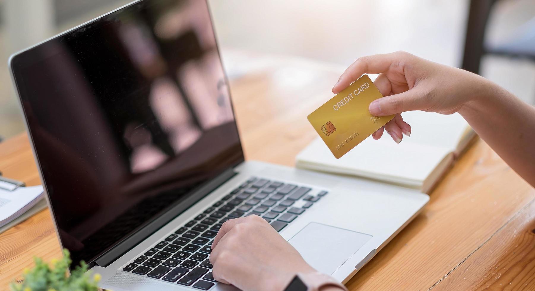 donna che usa il computer e tiene in mano una carta di credito per lo shopping online foto