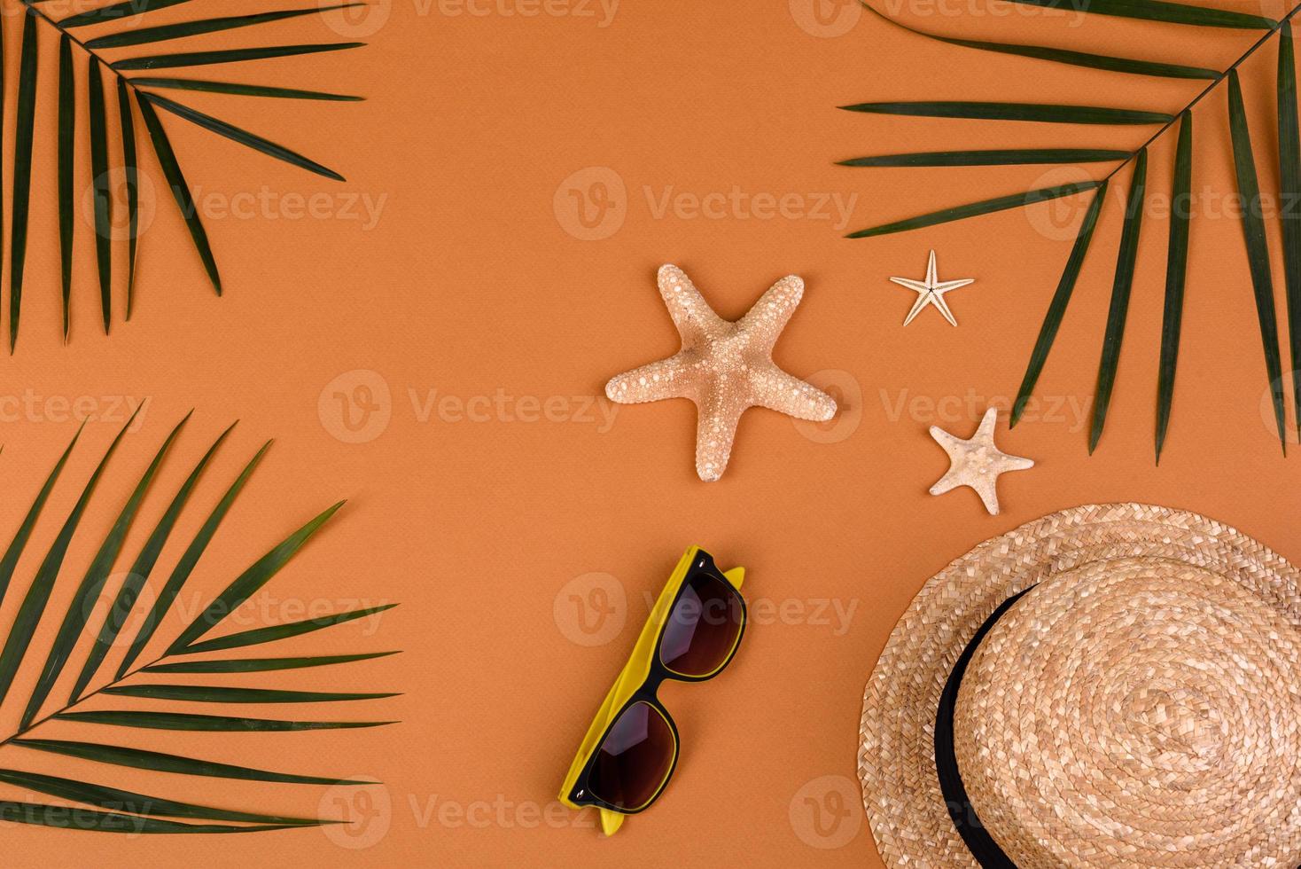 accessori da spiaggia, occhiali e cappello con conchiglie e stelle marine su sfondo colorato foto