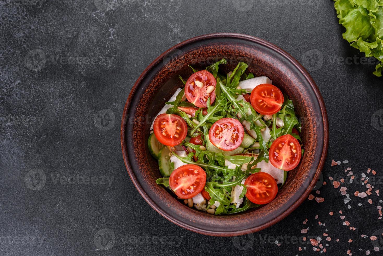 pezzi di pollo, pomodori e foglie di lattuga su uno sfondo di cemento scuro foto