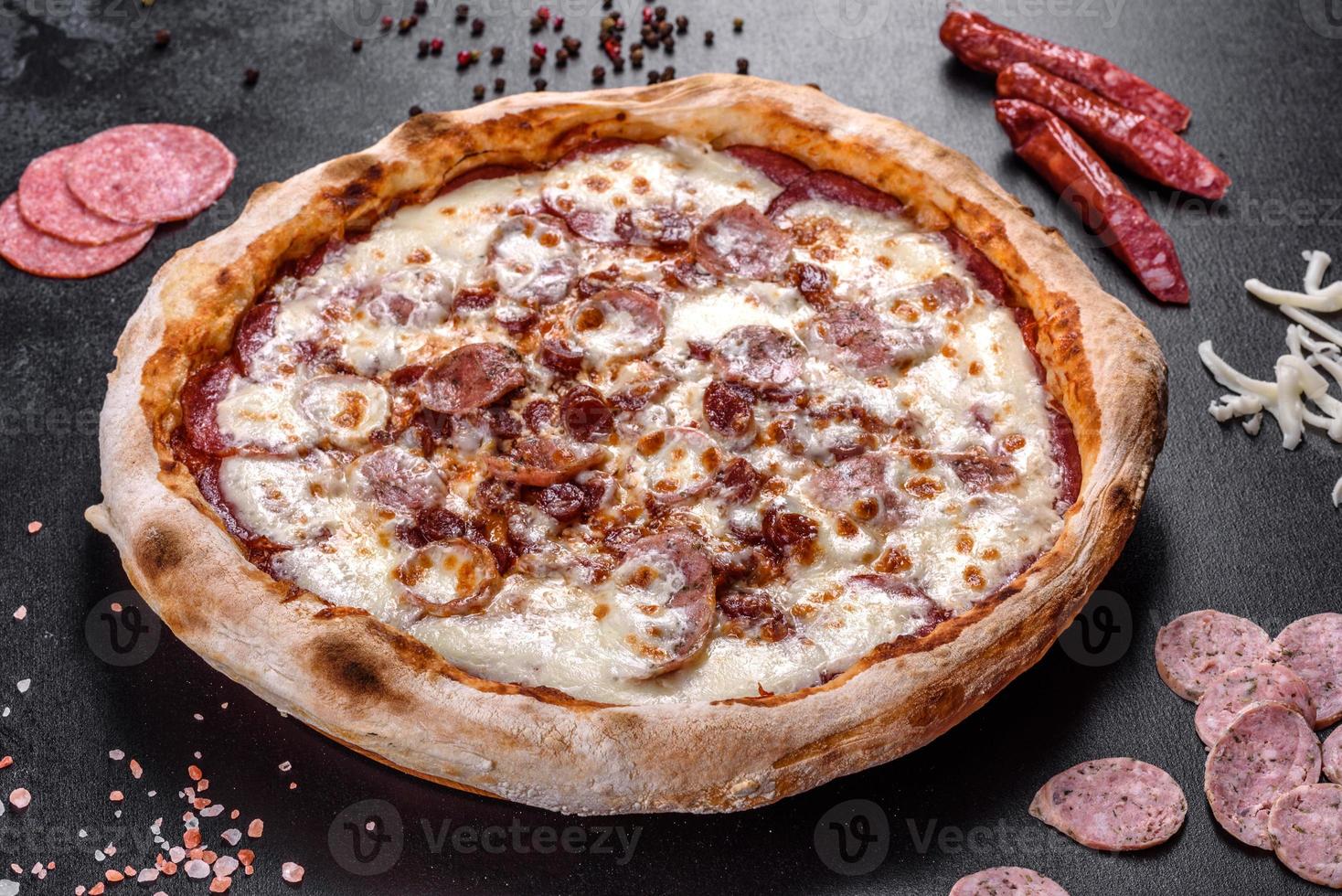 pizza italiana fresca e deliziosa con quattro tipi di carne su uno sfondo di cemento scuro foto