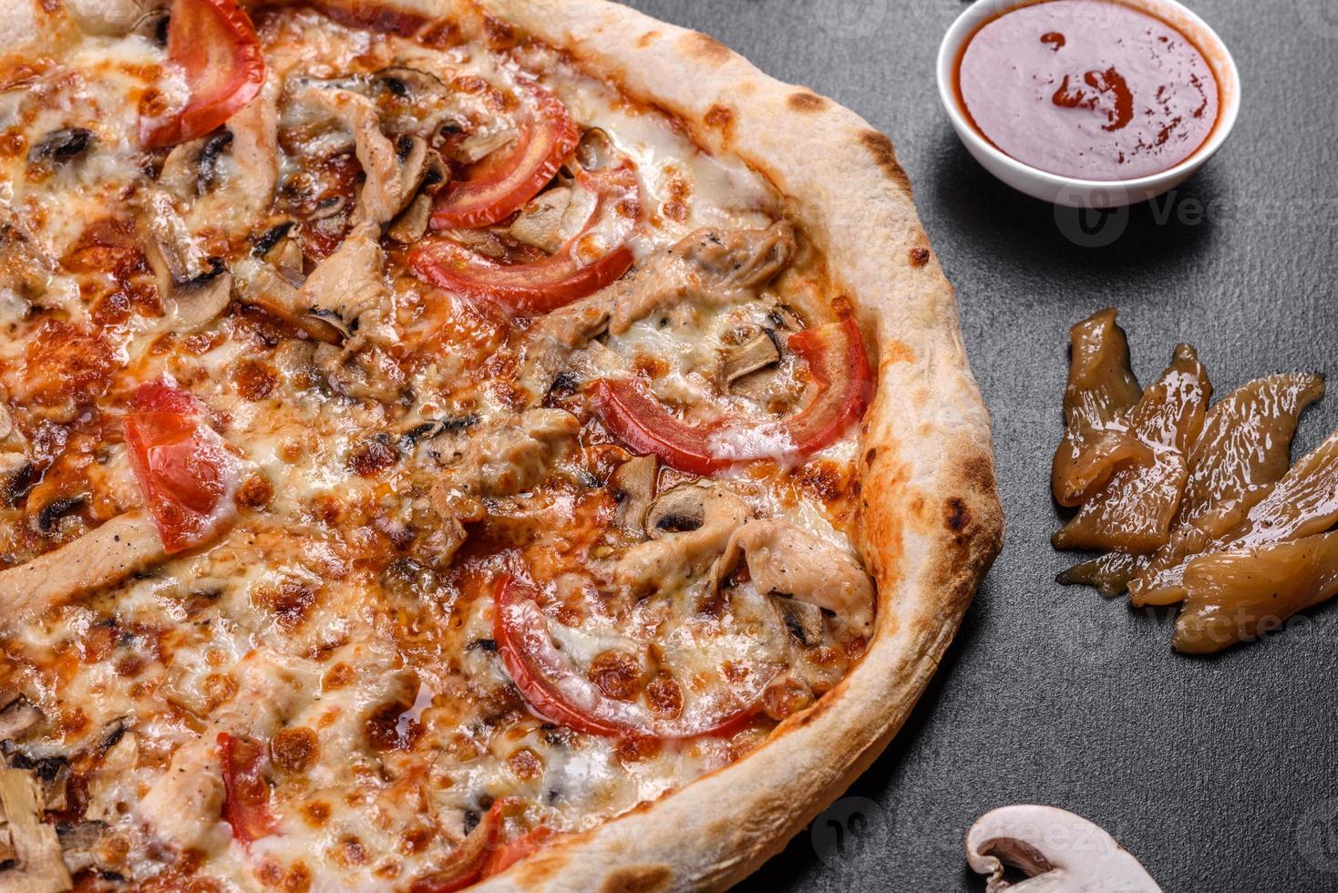 pizza italiana fresca e deliziosa con funghi e pomodori su uno sfondo di cemento scuro foto