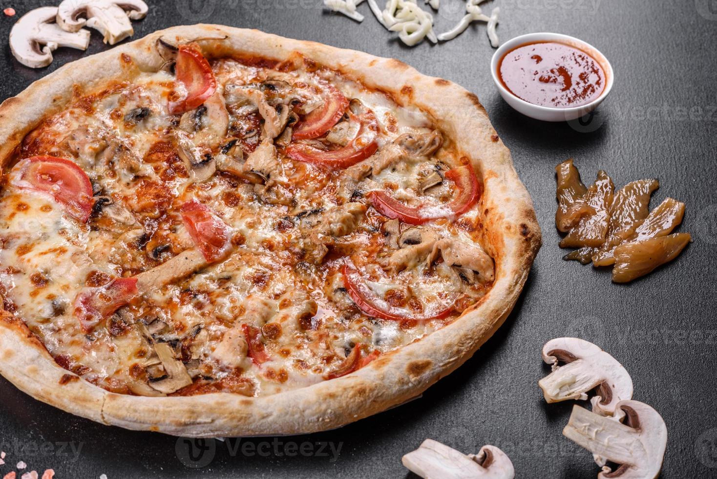 pizza italiana fresca e deliziosa con funghi e pomodori su uno sfondo di cemento scuro foto