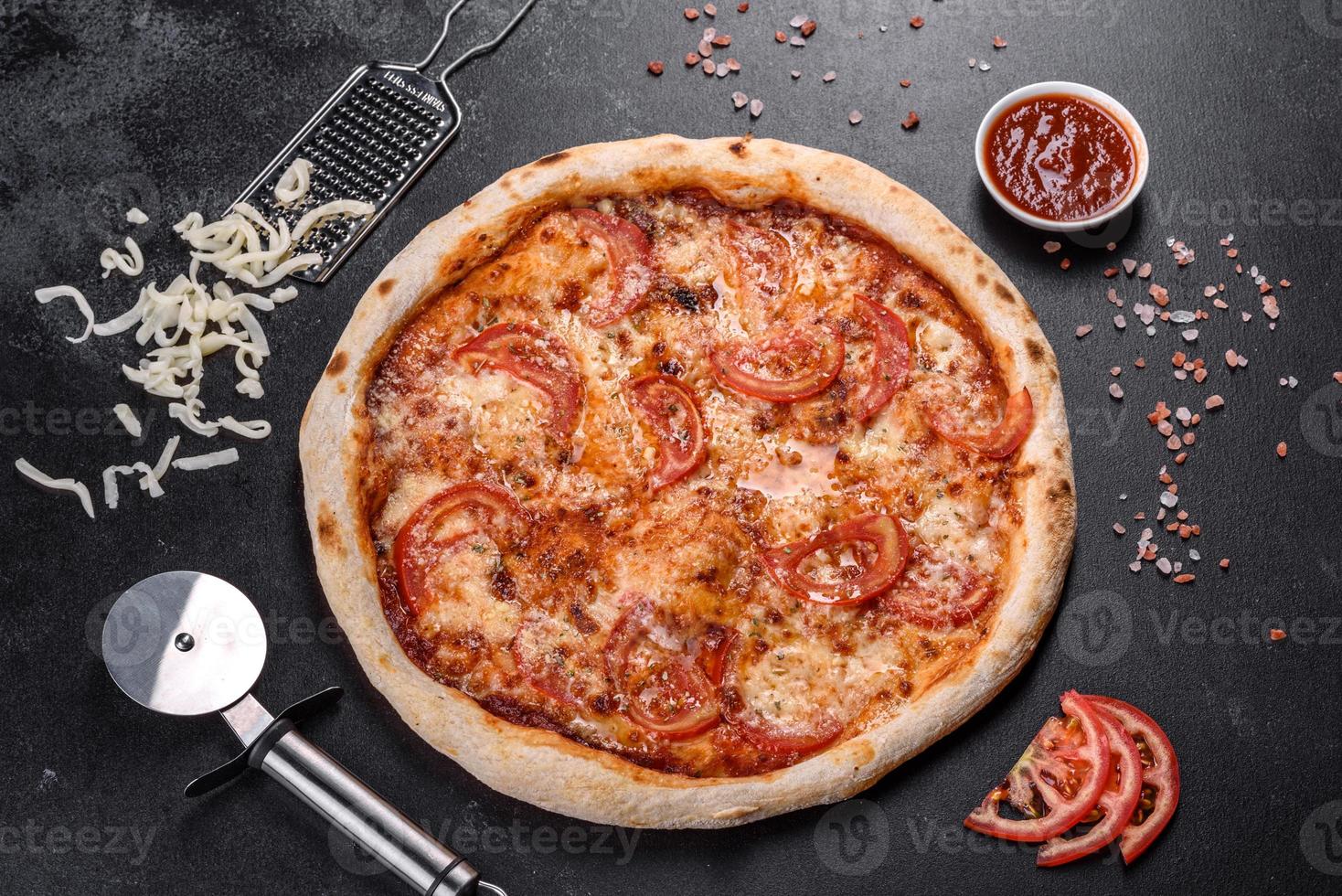 pizza italiana fresca e deliziosa con funghi e pomodori su uno sfondo di cemento scuro foto