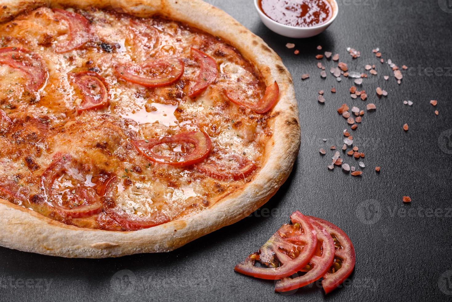 pizza italiana fresca e deliziosa con funghi e pomodori su uno sfondo di cemento scuro foto