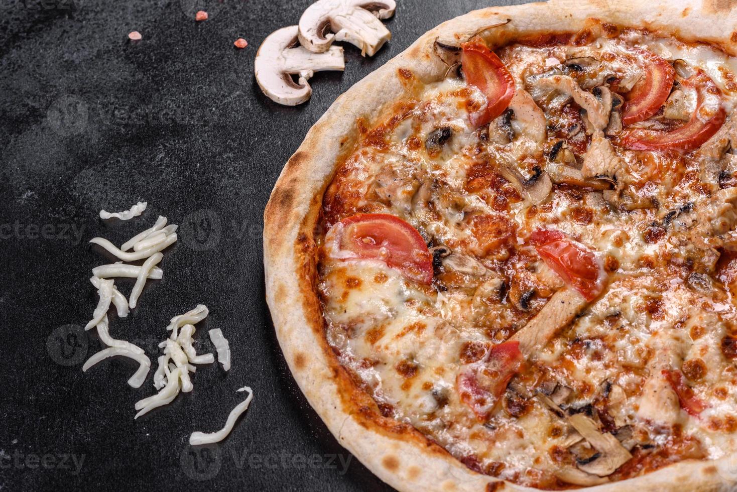 pizza italiana fresca e deliziosa con funghi e pomodori su uno sfondo di cemento scuro foto