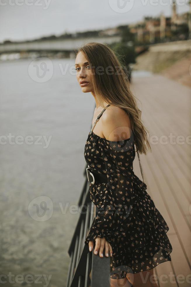 giovane donna bruna capelli lunghi in piedi sulla riva del fiume foto