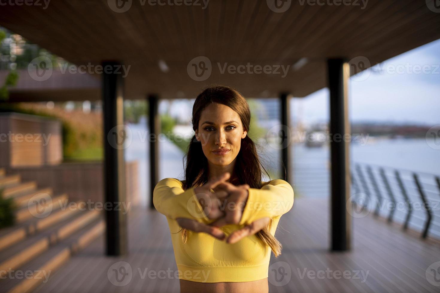 giovane donna che si estende sulla riva del fiume foto