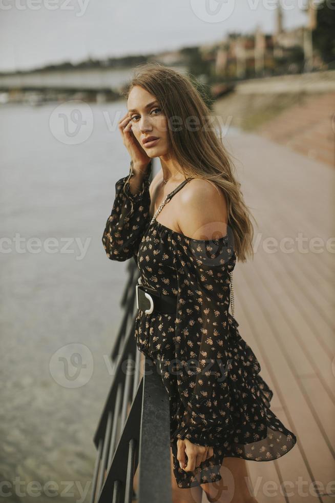 giovane donna bruna capelli lunghi in piedi sulla riva del fiume foto