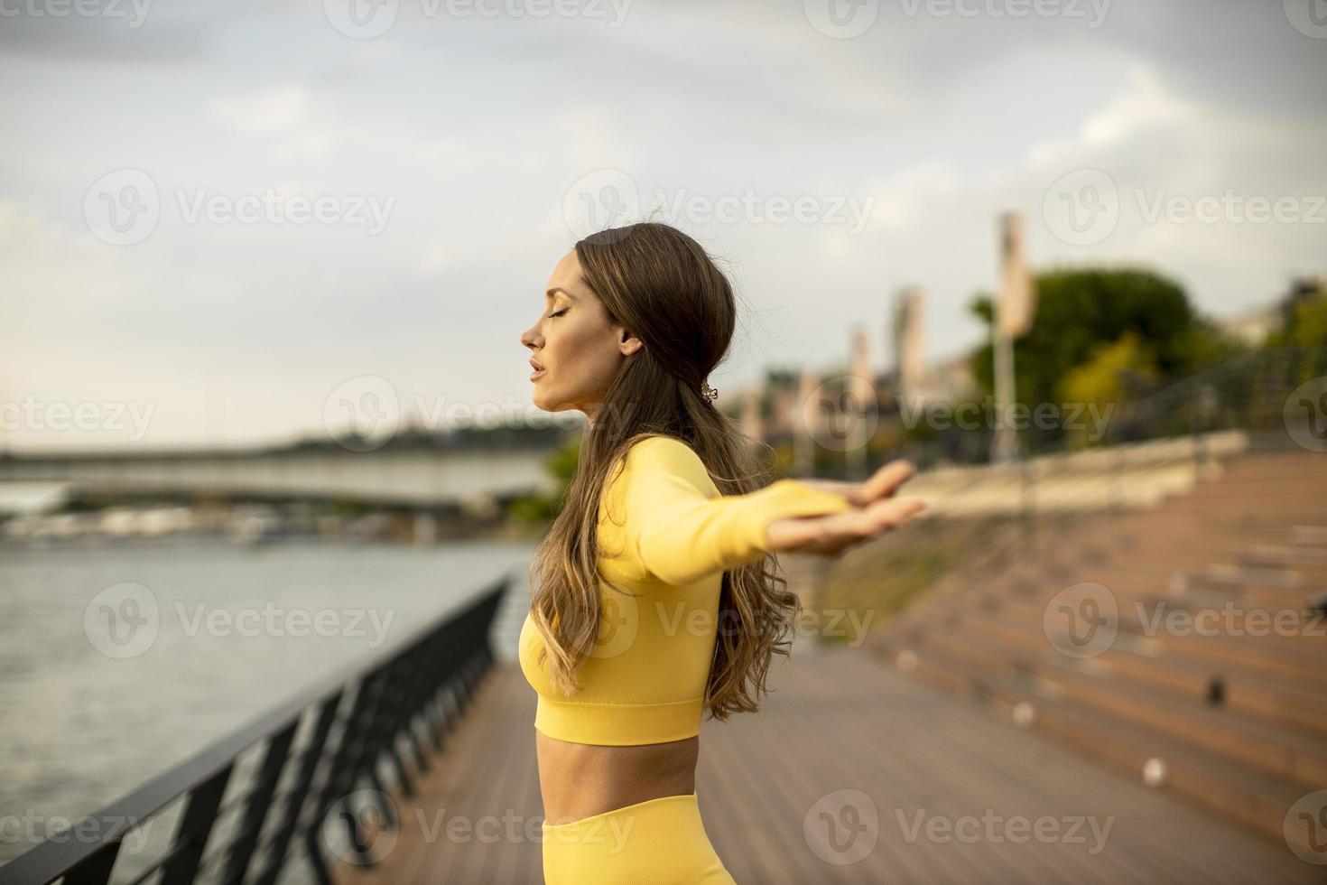 giovane donna che si estende sulla riva del fiume foto