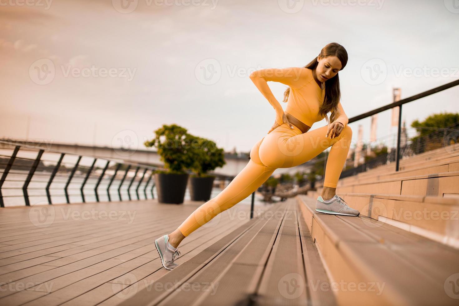 giovane donna che si estende sulla riva del fiume foto