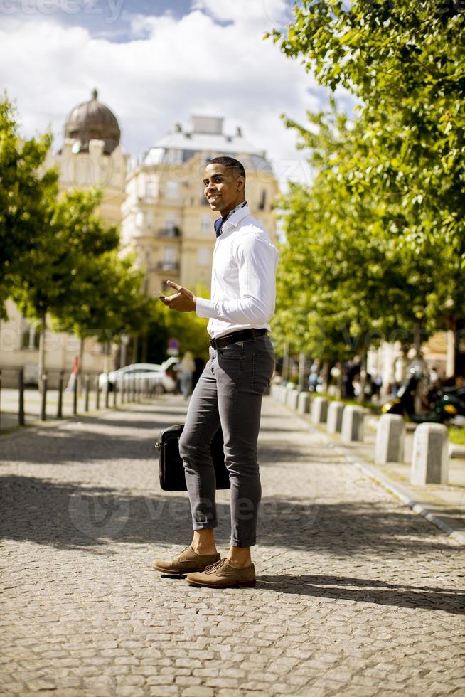 giovane uomo d'affari afroamericano utilizzando un telefono cellulare in una strada foto